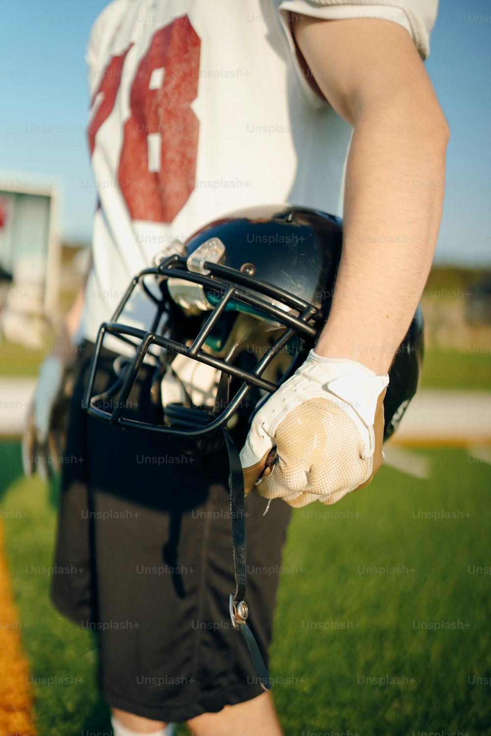 a football player holding a helmet on a field