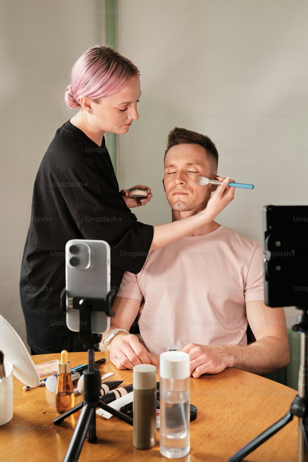 a man getting his makeup done by a woman