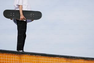 a person holding a skateboard on top of a wall