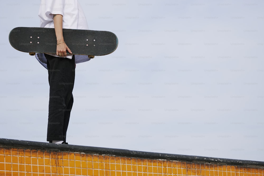 una persona che tiene uno skateboard in cima a un muro