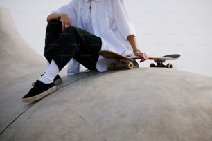 a man sitting on top of a cement structure holding a skateboard