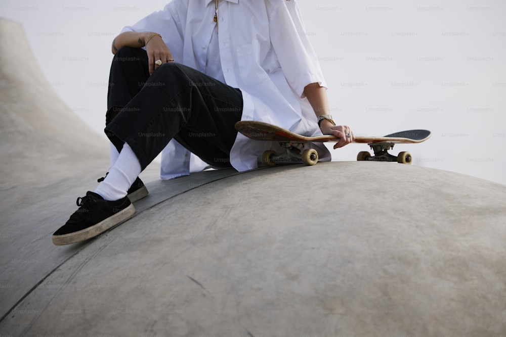 ein mann, der auf einer zementkonstruktion sitzt und ein skateboard hält