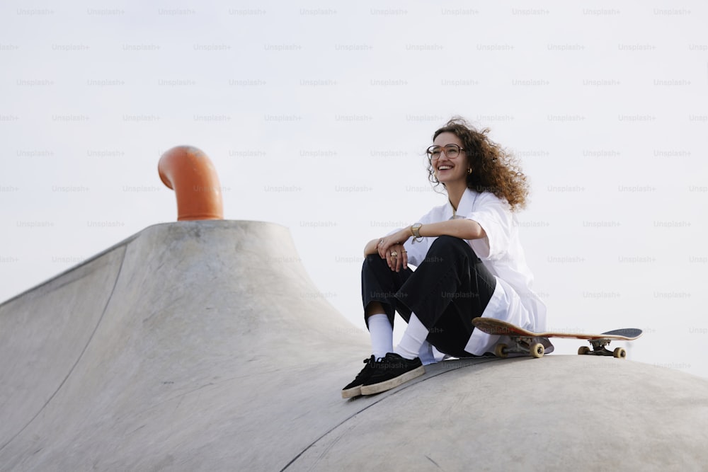 a woman sitting on top of a skateboard ramp