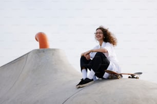 Una mujer sentada en la parte superior de una rampa de patineta