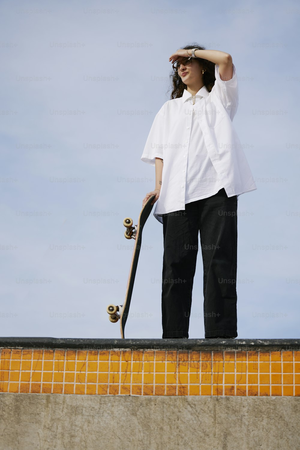 Una mujer sosteniendo una patineta en la parte superior de una rampa