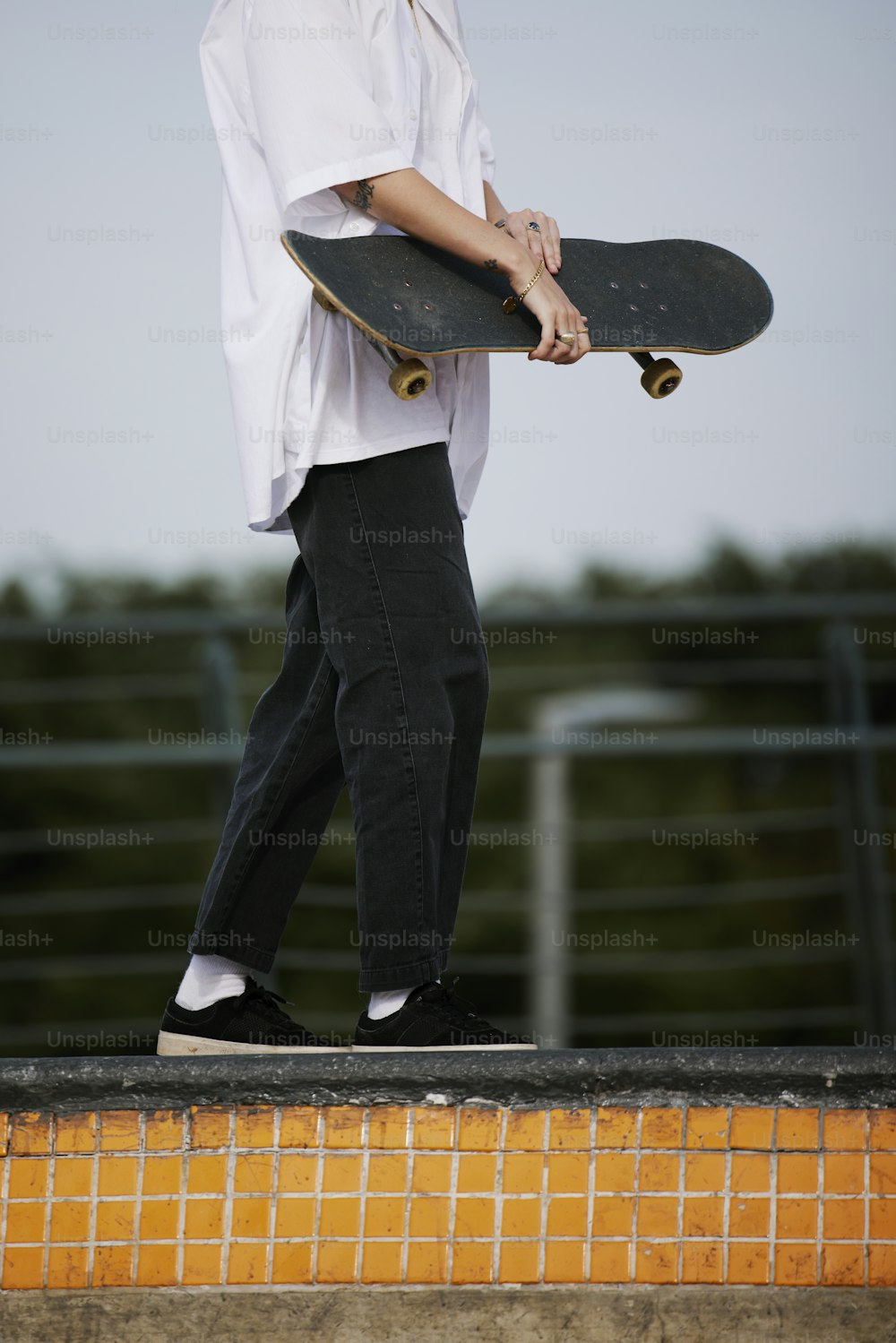 a man holding a skateboard while standing on a ledge