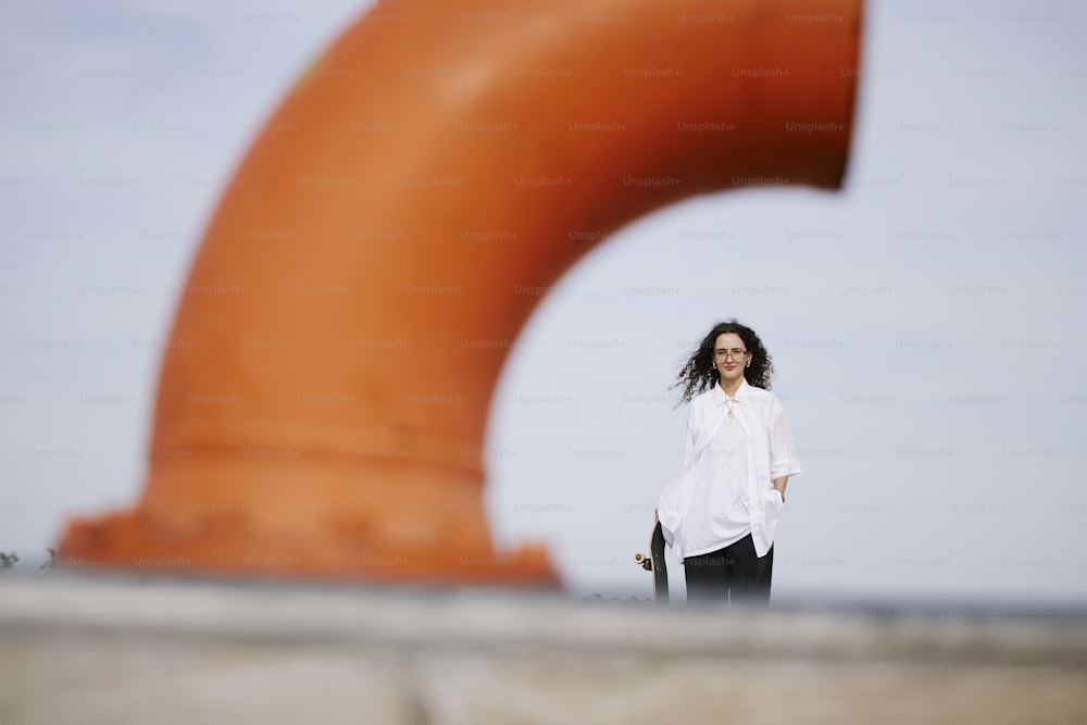 a woman standing in front of a large orange object