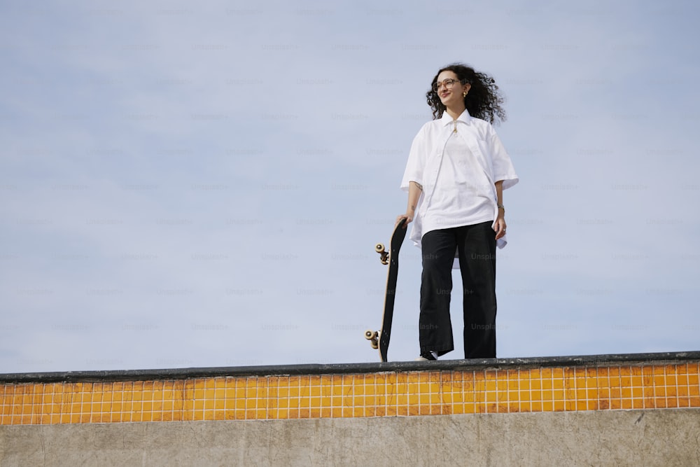 Una mujer sosteniendo una patineta en la parte superior de una rampa