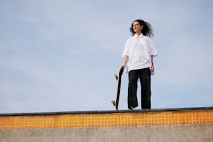 a woman holding a skateboard on top of a ramp