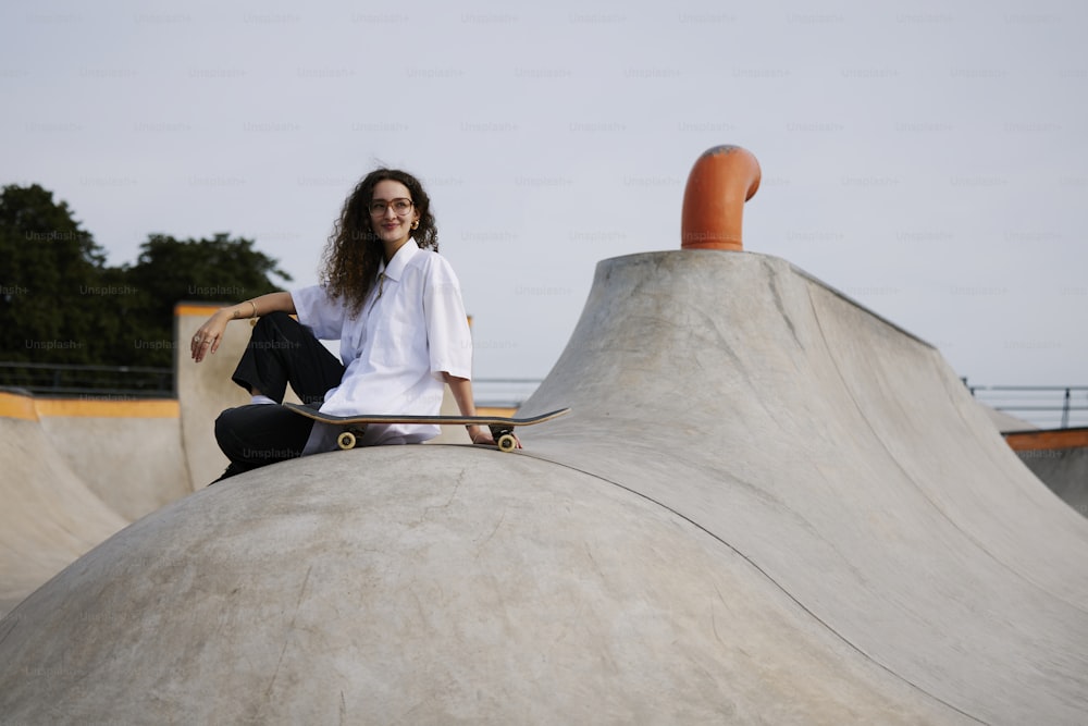 a woman sitting on top of a skateboard ramp