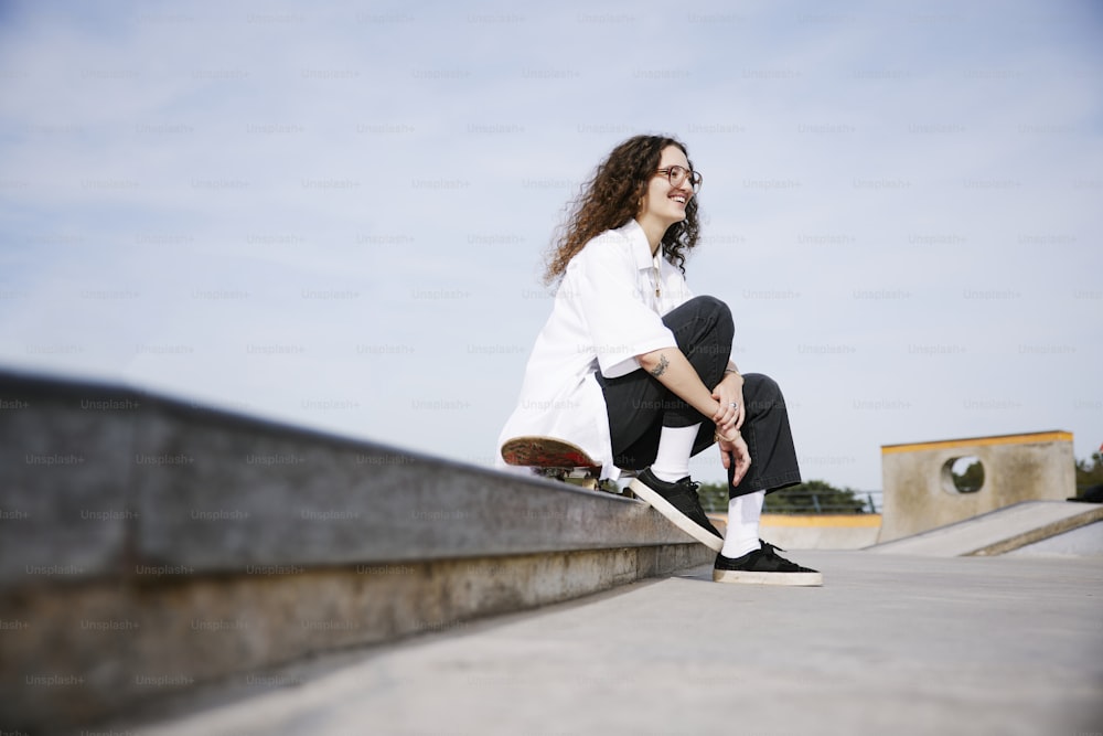 a person sitting on a ledge with a skateboard