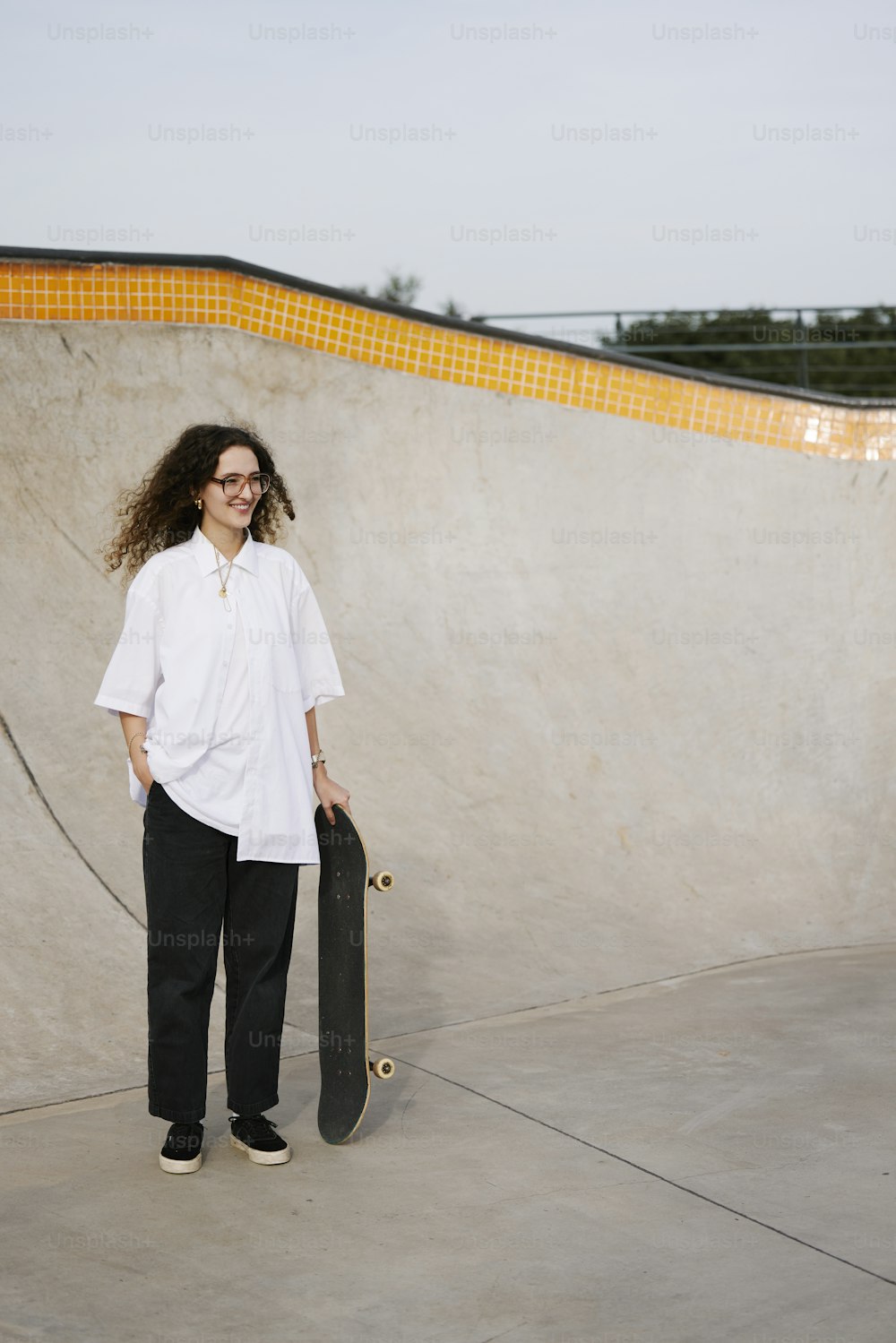 a woman holding a skateboard in a skate park