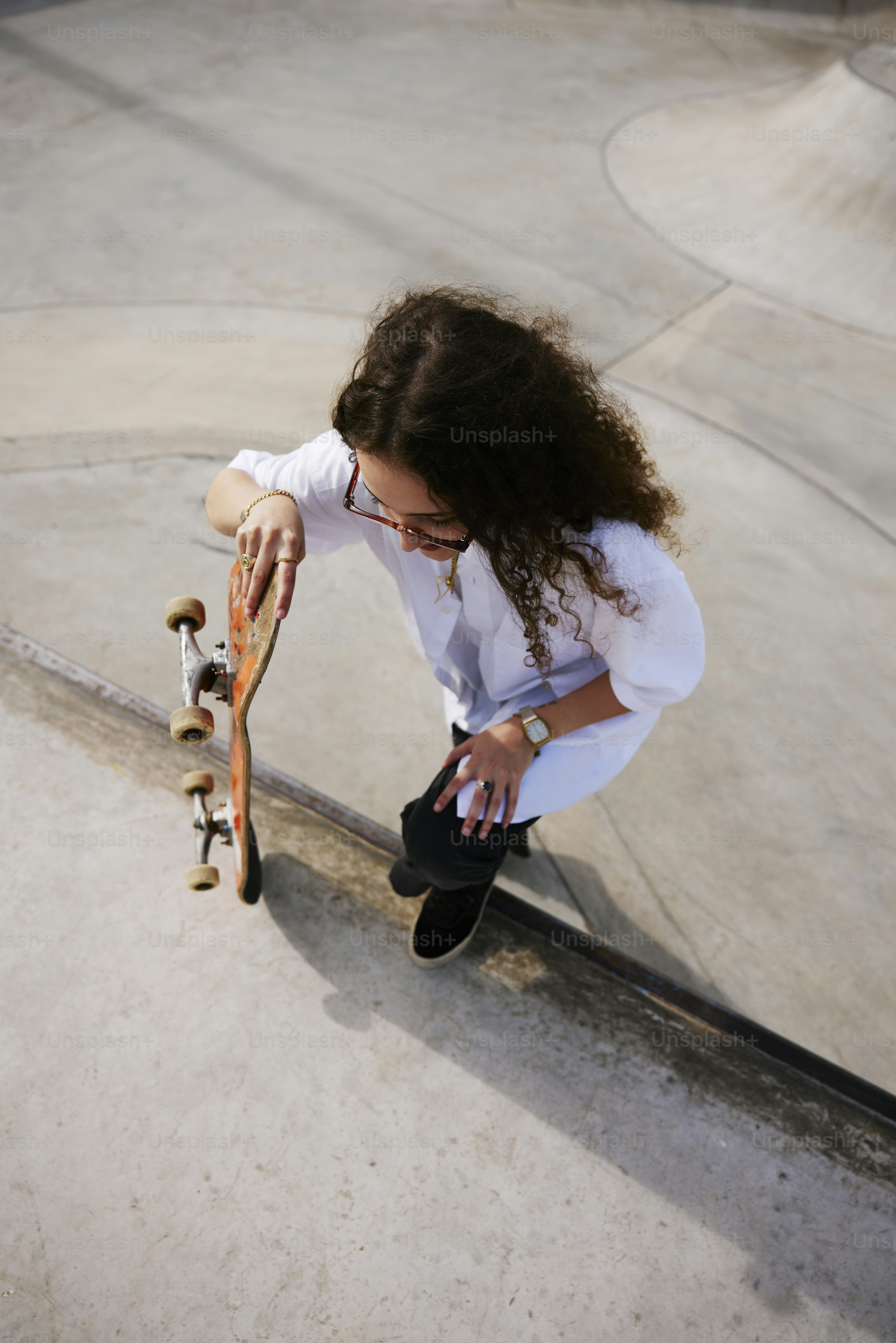 a young woman holding a skateboard on top of a ramp