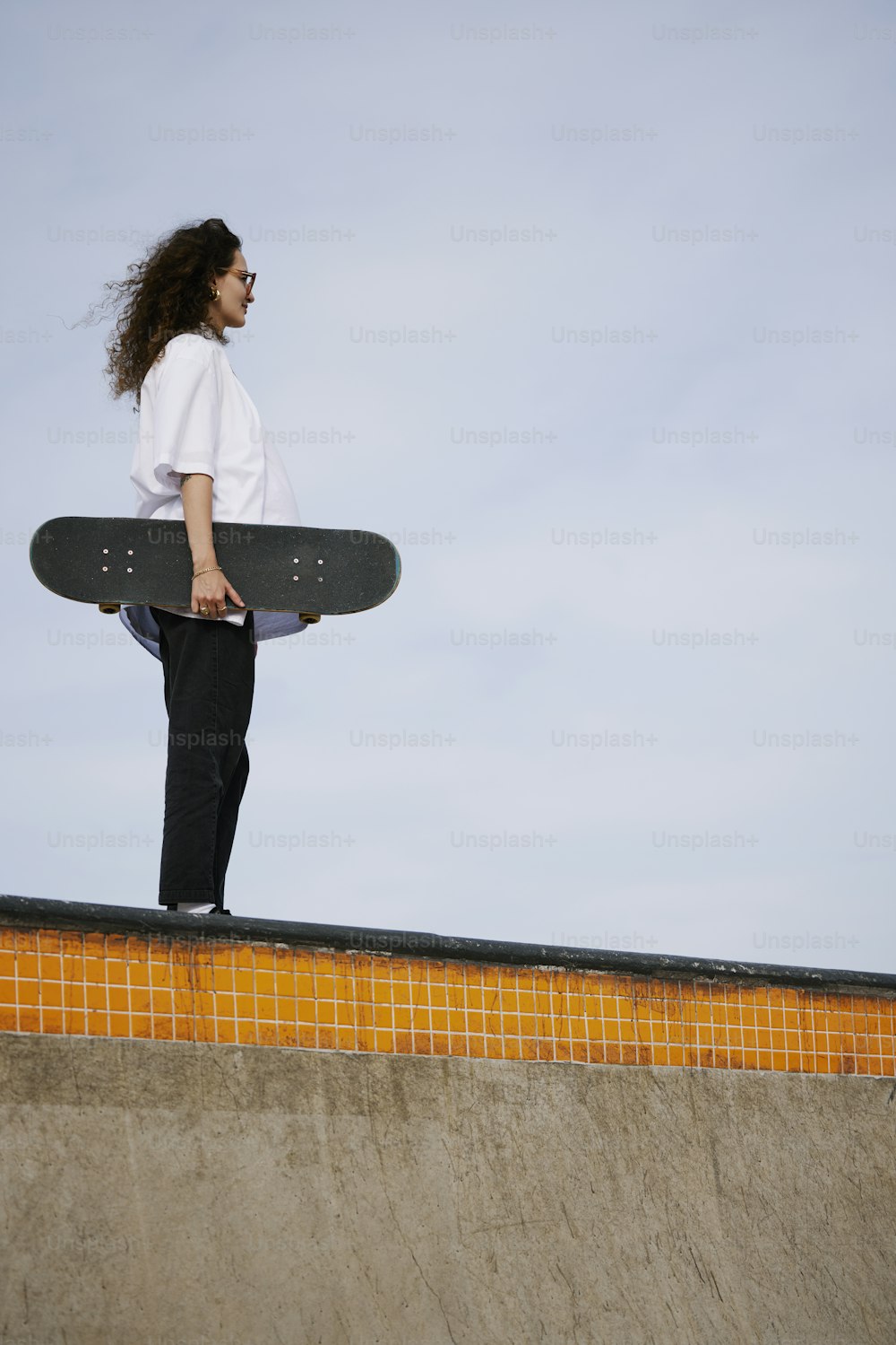 a woman holding a skateboard on top of a ramp