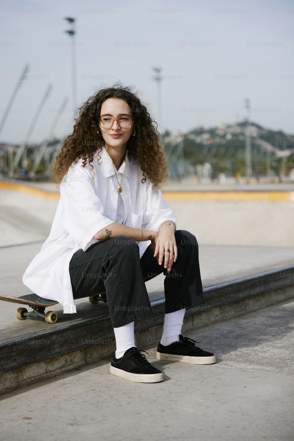 a woman sitting on a ledge with a skateboard