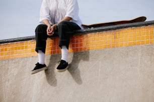 a man sitting on top of a skateboard ramp