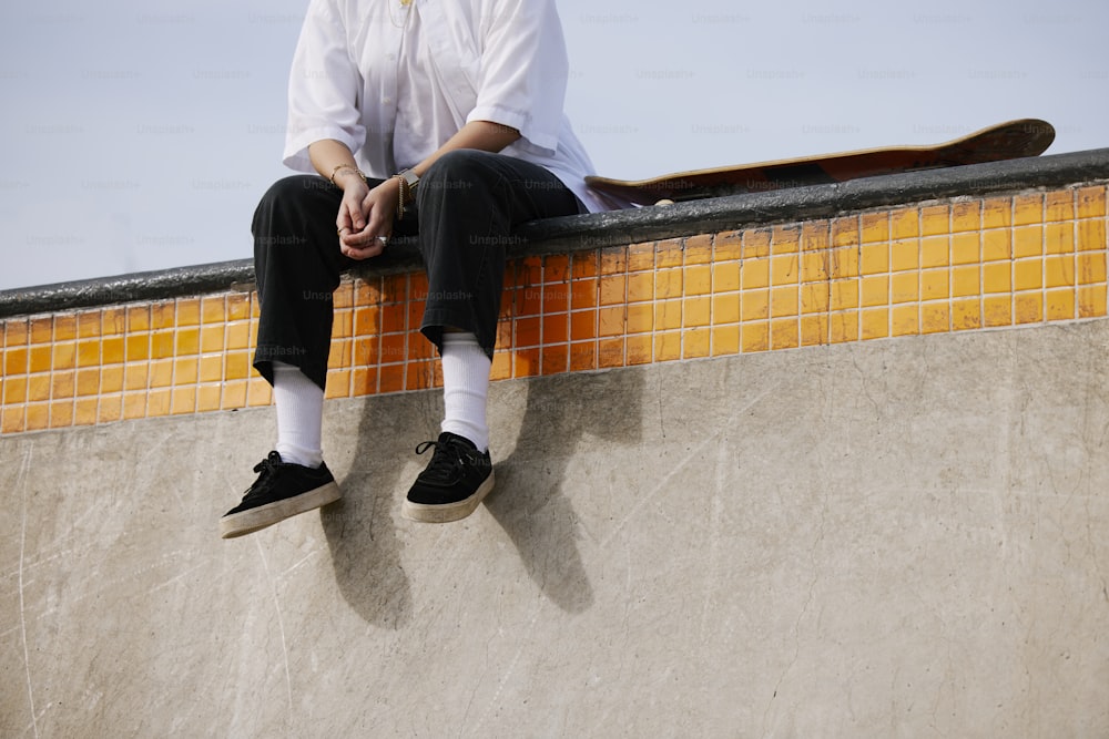 a man sitting on top of a skateboard ramp