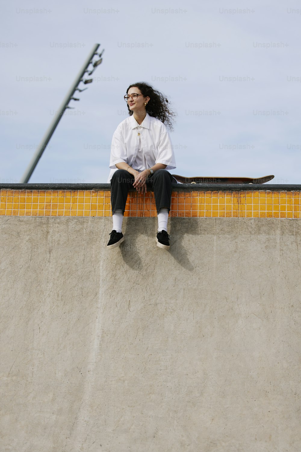 a woman sitting on top of a skateboard ramp