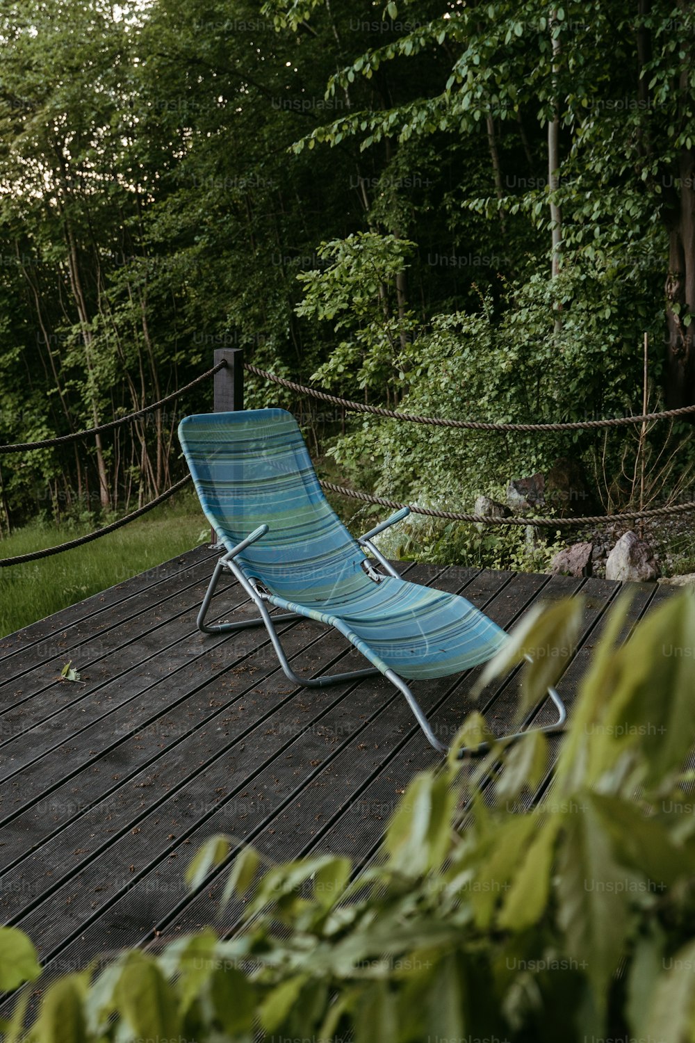 a blue lawn chair sitting on top of a wooden deck