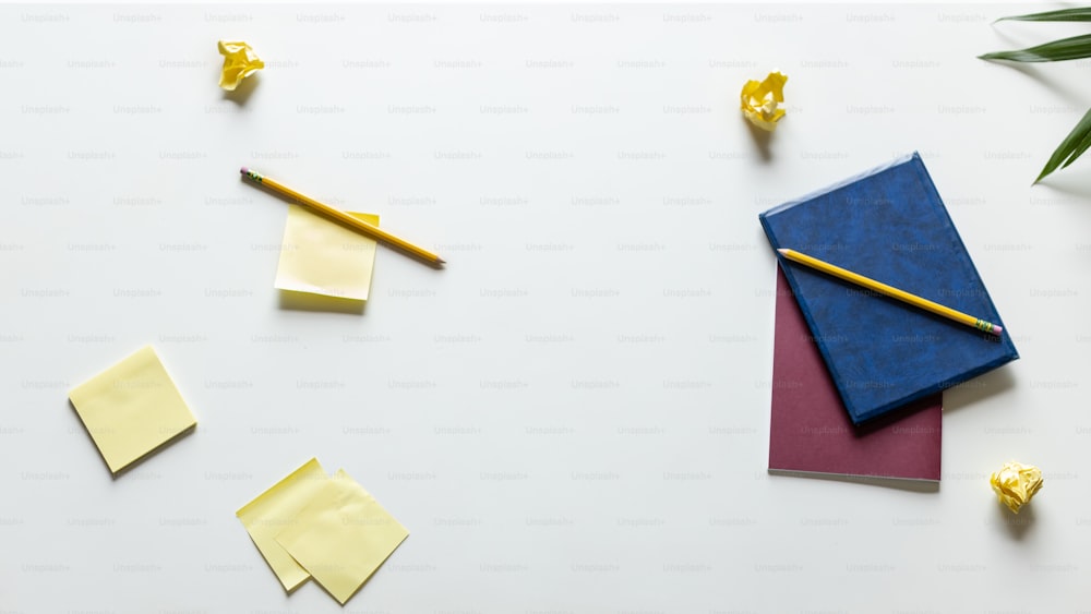 um caderno, lápis e notas adesivas em uma superfície branca