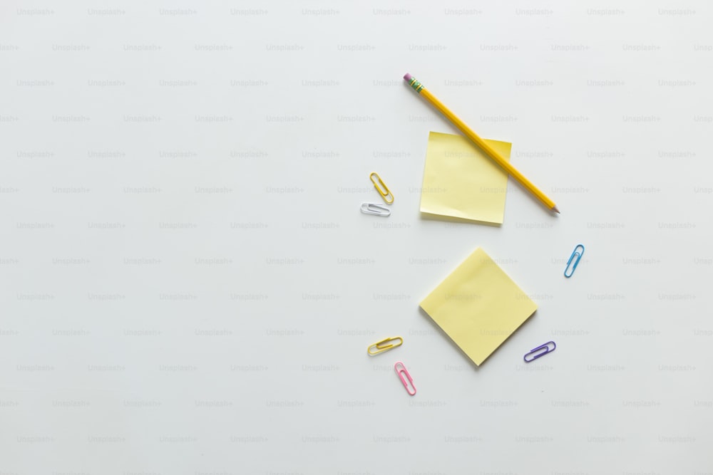 a white table topped with yellow sticky notes and a pencil