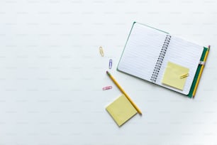 un cahier, un crayon et une gomme sur une surface blanche