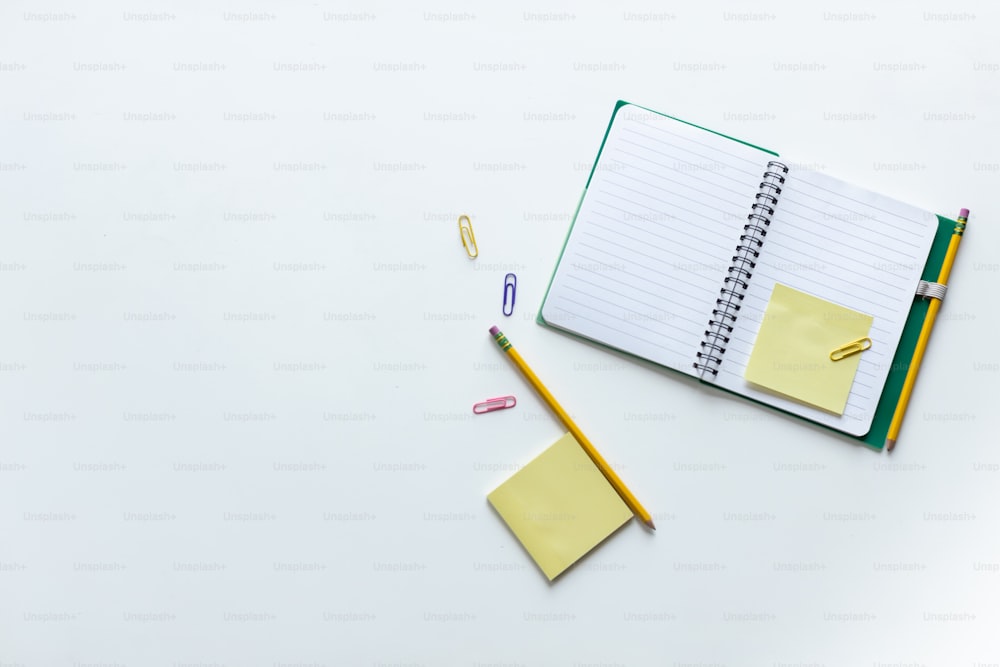 a notebook, pencil, and eraser on a white surface