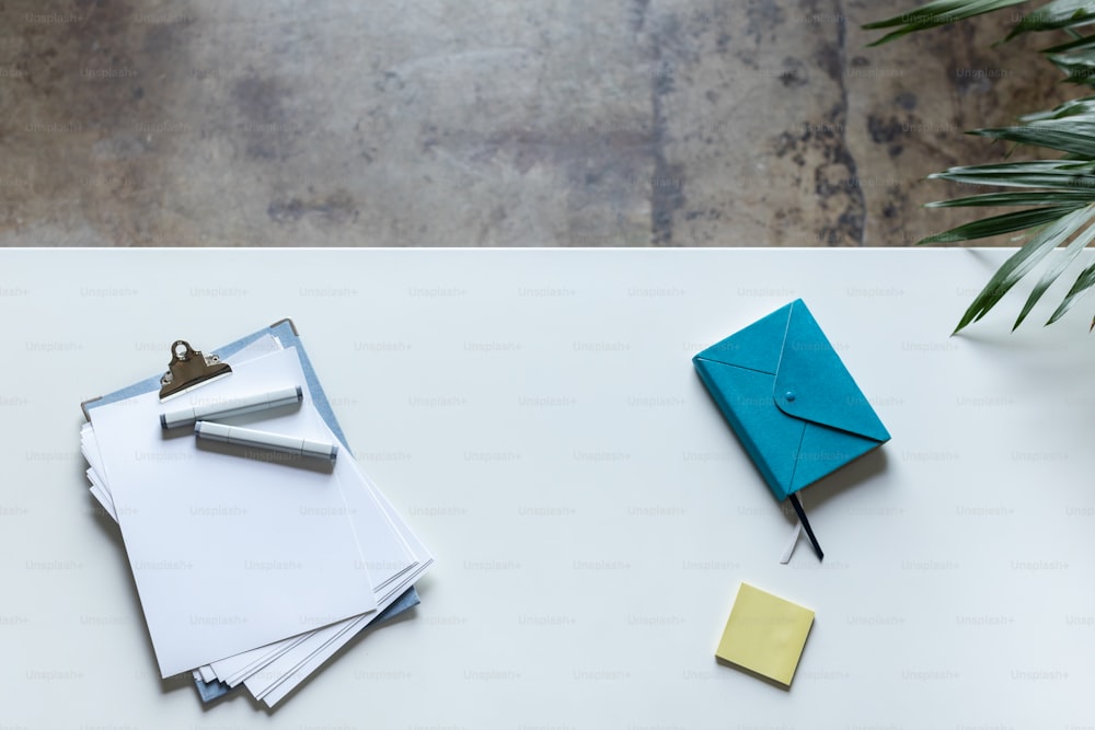 a white table topped with lots of papers and a plant