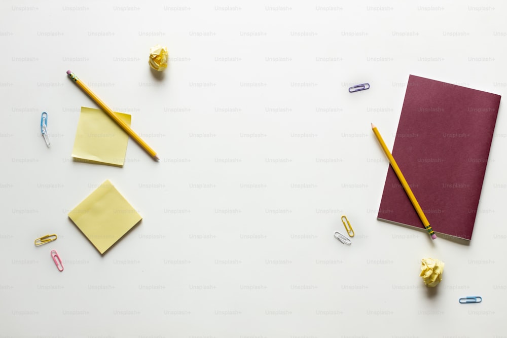 un cahier, des crayons et d’autres fournitures de bureau sur une surface blanche