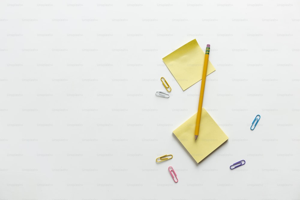 einen gelben Umschlag mit Bleistift, Büroklammern und einer Schere