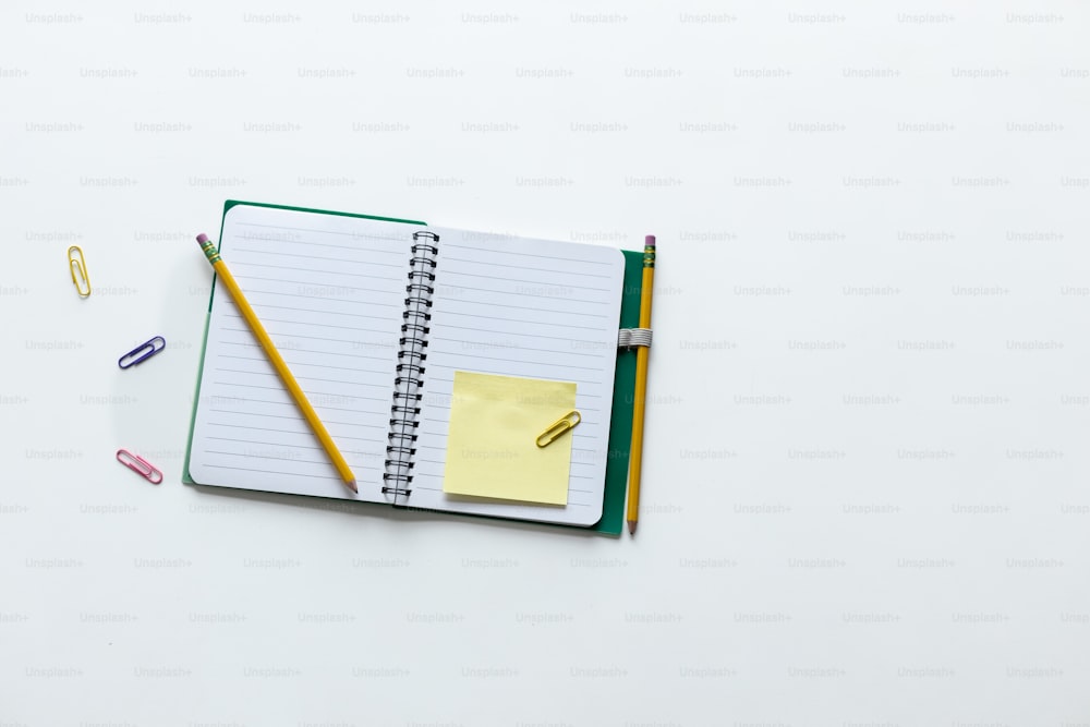 un cuaderno con un bloc de notas y lápices encima