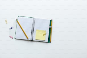 a notebook with a notepad and pencils on top of it