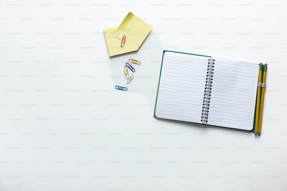 Notizblock, Kugelschreiber, Bleistift und Papier auf weißer Fläche