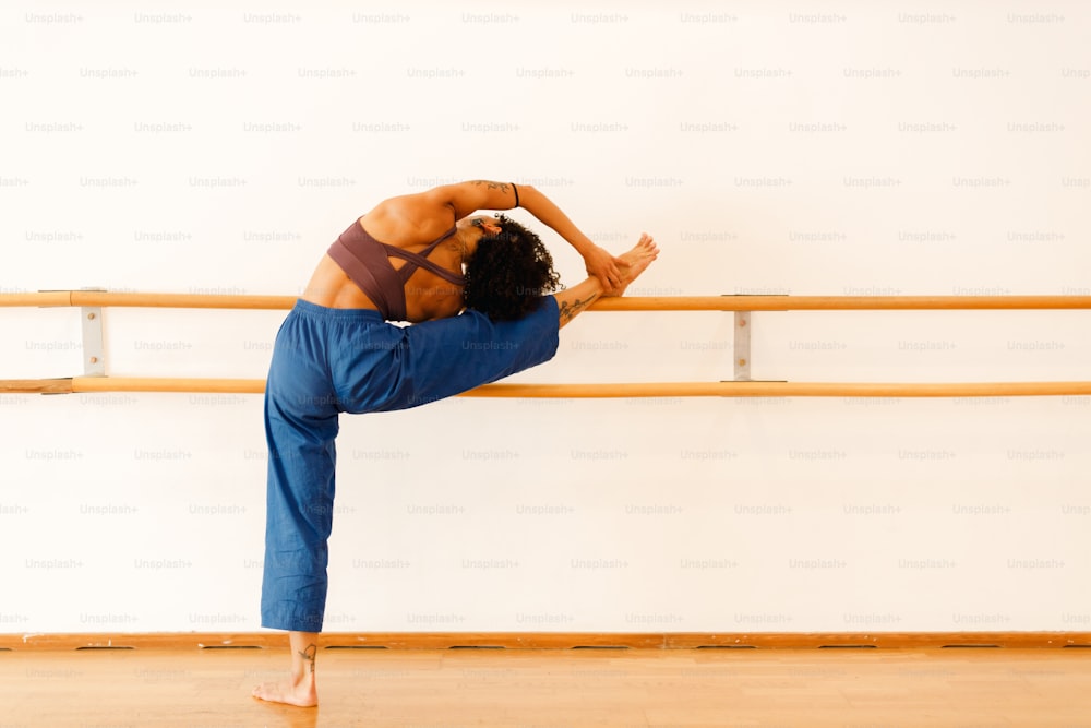 a woman doing a yoga pose in front of a wooden rail