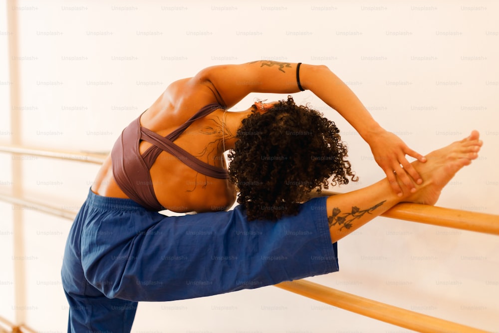 Une femme faisant une pose de yoga sur un rail en bois