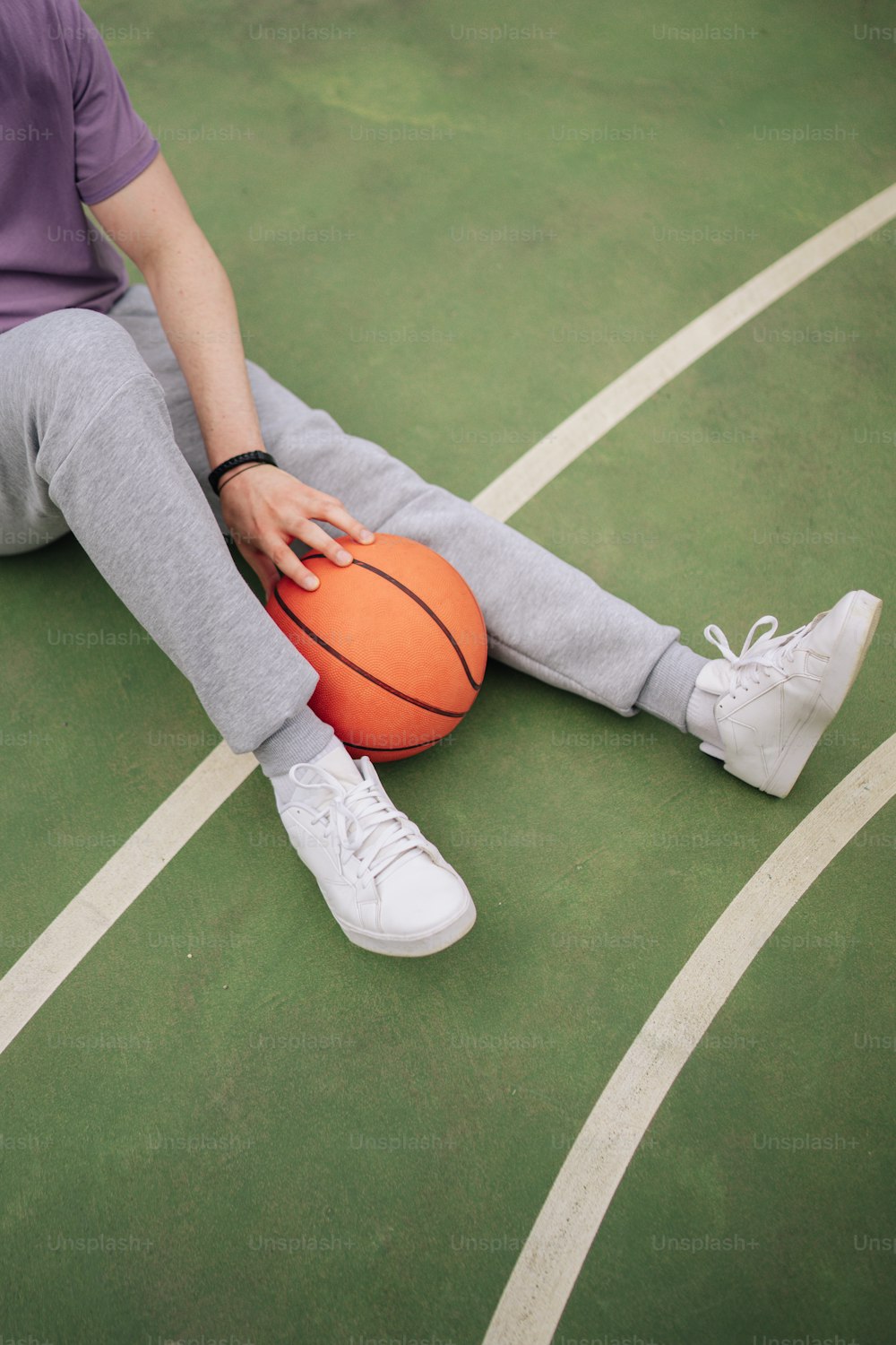 a person sitting on a court with a basketball