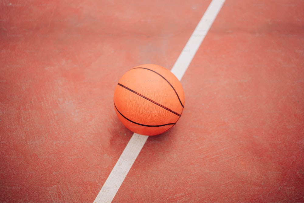 Una pelota de baloncesto sentada en una cancha con una línea blanca