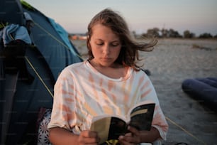 Una niña leyendo un libro en la playa
