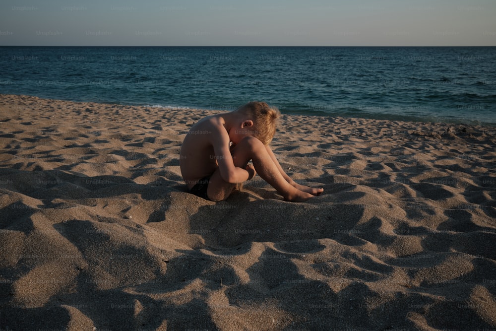 eine person, die im sand am strand sitzt