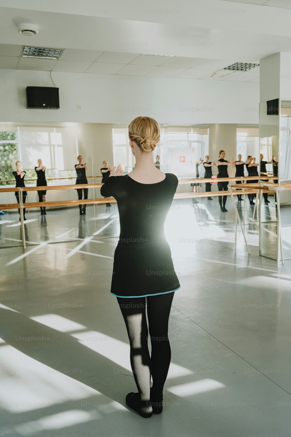a woman in a black dress standing in a dance studio