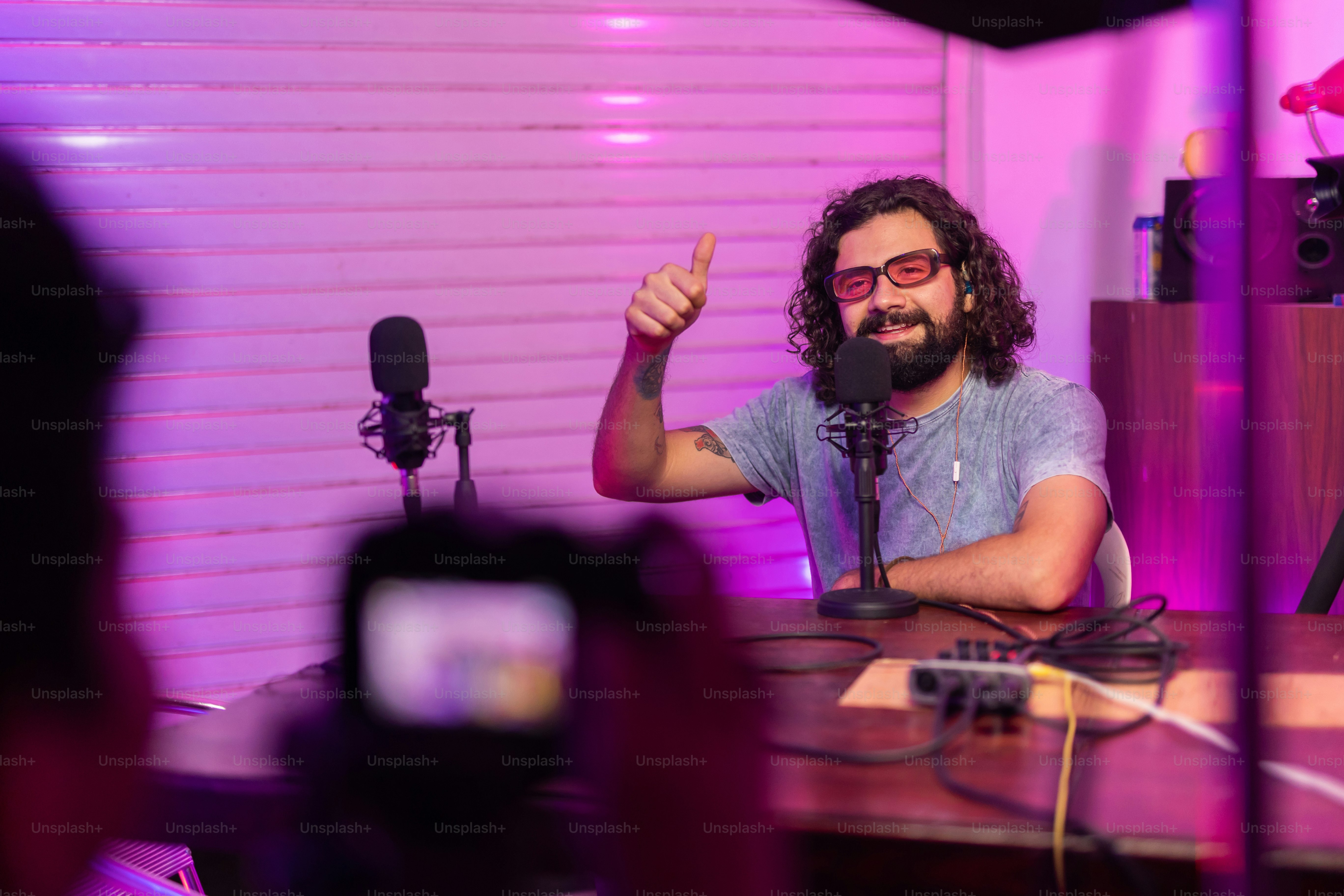 a man giving a thumbs up while sitting in front of a microphone