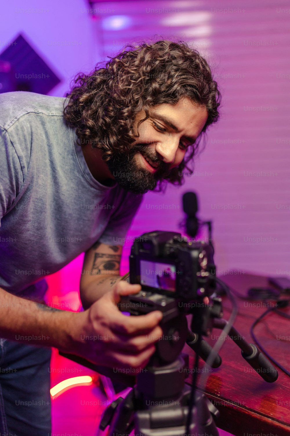 a man holding a camera in front of a purple light