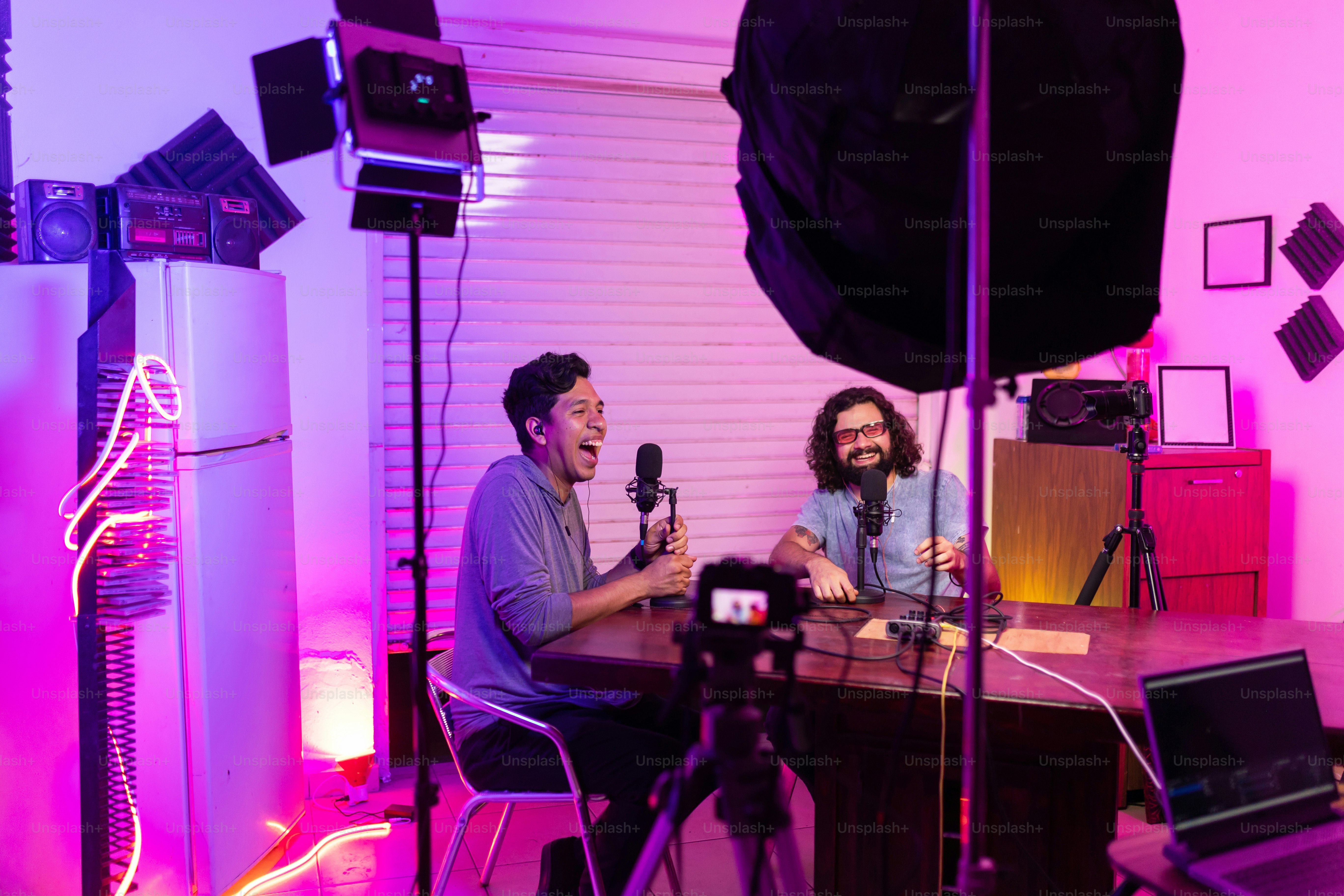 a couple of men sitting at a table with microphones