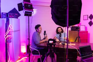 Un par de hombres sentados en una mesa con micrófonos