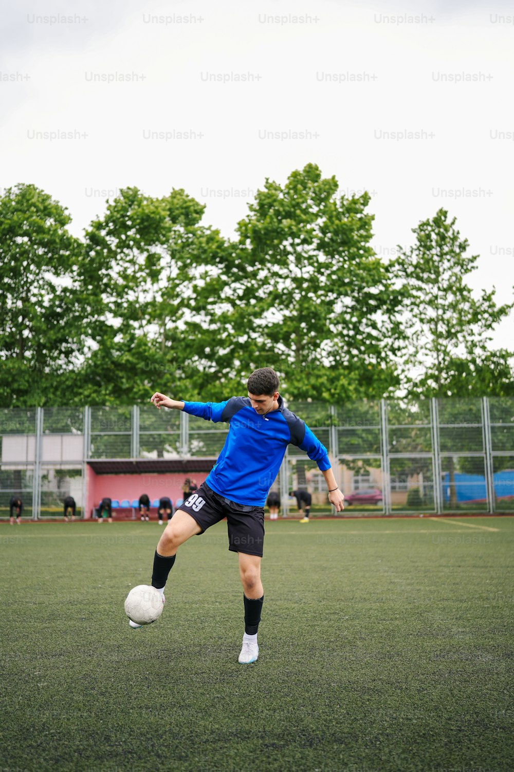 フィールドでサッカーボールを蹴る若い男