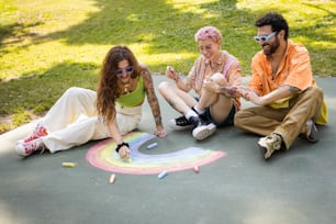 a group of people sitting on the ground drawing a rainbow