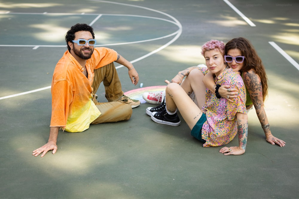 バスケットボールコートに座る男性と2人の女性