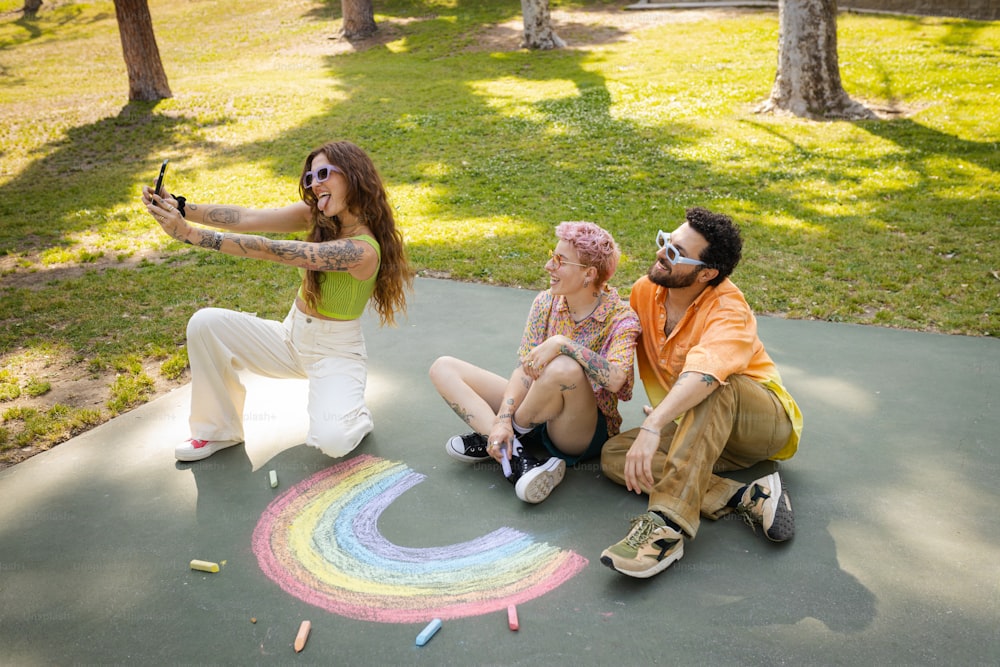 eine gruppe von menschen, die auf dem boden sitzen, mit einem regenbogen auf dem boden gezeichnet