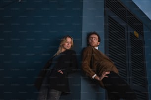 a man and a woman leaning against a wall