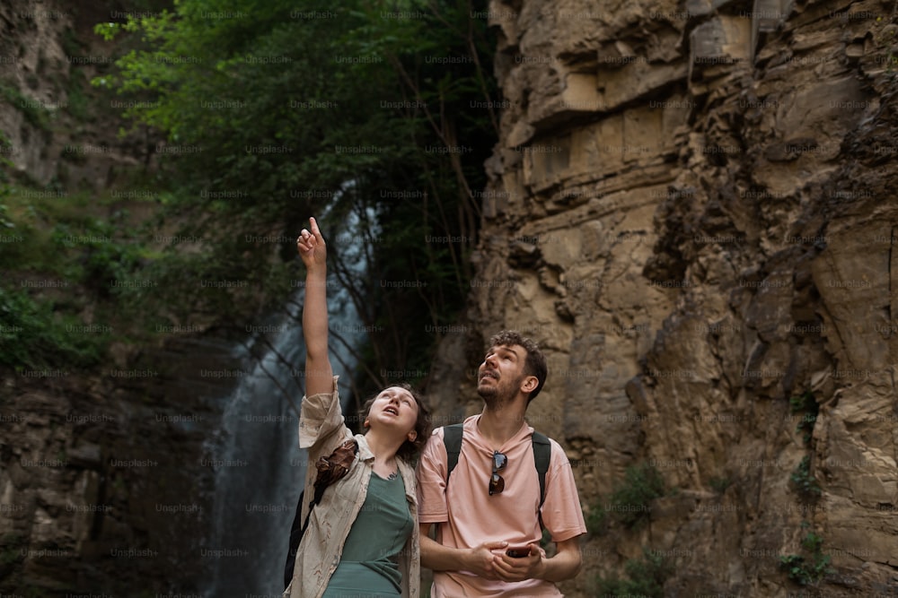 a man and a woman standing in front of a waterfall